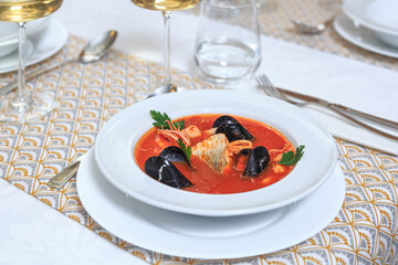 seafood tomato soup served with a knife and fork with a glass of water and wine