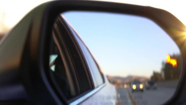 Blurry reflection in car side view mirror of other cars on the road.