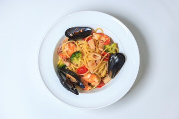 spaghetti pasta with seafood and cherry tomatoes on a white plate on a pure white table