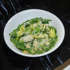 green salad in a deep white salad bowl served on a black marble table