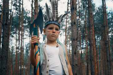 A portret of a boy dressed as an American Indian in the forest