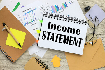 income statement text on the page. notepad with spring on paper with graphs