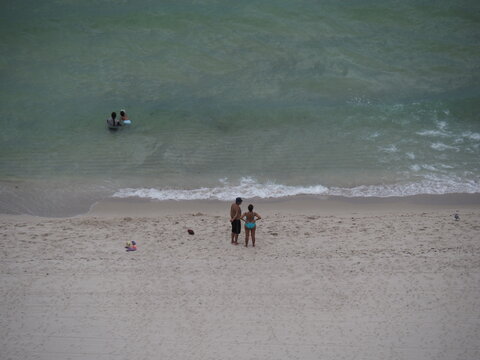 Couple discussing whether to leave the beach as a thunderstorm approaches from offshore.  