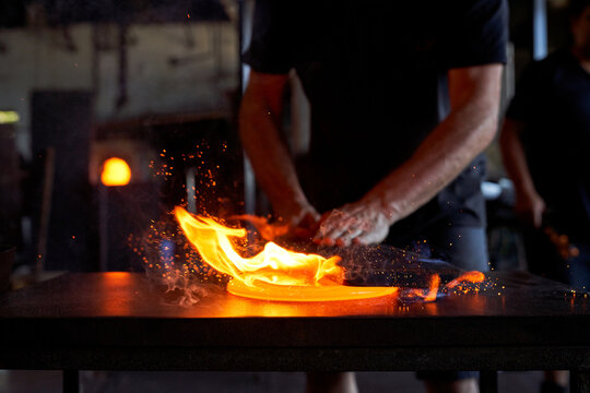 Crop craftsman making glass product in glassblowing workshop - Powered by Adobe