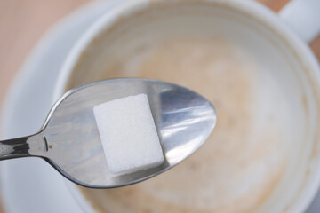 pouring white sugar cube in a coffee cup , top view 