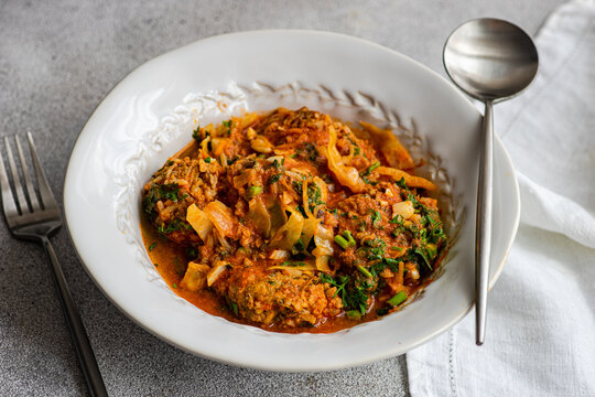 Georgian Gupta dish of meatballs with rice stewed in tomato sauce with cabbage, carrot and onion, served with chopped coria
