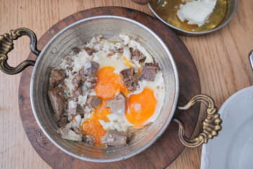Turkish scrambled eggs with roasted meat in copper pan