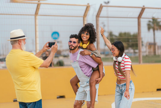 Cheerful friends taking pictures on playground - Powered by Adobe