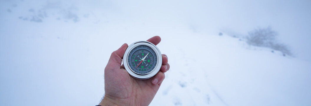 man hand compass in snowy mountain