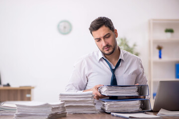 Naklejka premium Young male employee and too much work in the office