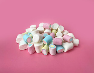 Obraz na płótnie Canvas A handful of colorful marshmallows on a pink background, side view.