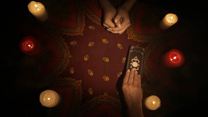 Top view, fortune teller offers a deck of tarot cards to the female client, she picks few cards.