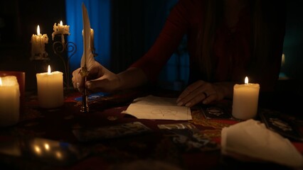Woman sitting on the table in the dark room and writes a letter with ink feather pen.