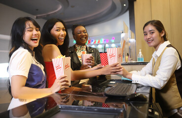 Friend girls are buying popcorn in cinema bar for happy enjoying a movie, popcorns and beverages over the weekend.