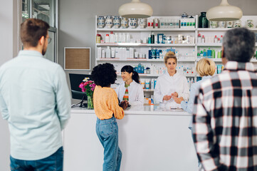 A queue of people standing in a pharmacy while shopping for medicine