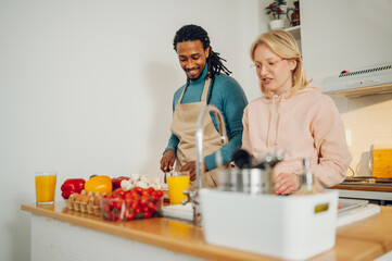 A cheerful multiracial couple is cooking a healthy meal at home.
