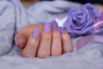 Close-up of well-groomed female nails with lilac and purple color gel. Beautiful clear fingers of a young girl with nice manicure. Brilliant colors and soft tones.