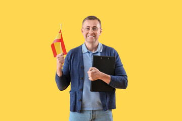 Mature man with flag of Spain and clipboard on yellow background