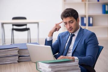 Obraz premium Young male employee and too much work in the office