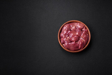 Fresh raw chicken or turkey liver in a ceramic plate with salt, spices and herbs