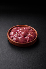 Fresh raw chicken or turkey liver in a ceramic plate with salt, spices and herbs