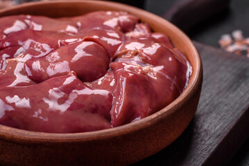 Fresh raw chicken or turkey liver in a ceramic plate with salt, spices and herbs