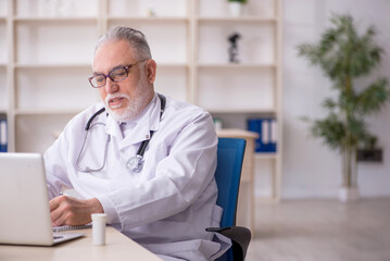 Old male doctor in telemedicine concept