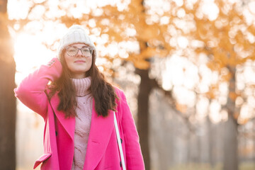 Happy stylish woman wear pink autumn jacket and knitted hat walk on city street outdoor. Fall...