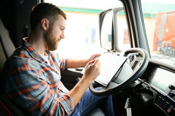 forwarder driver sits behind the wheel of a car and examines waybills documentation for the cargo.