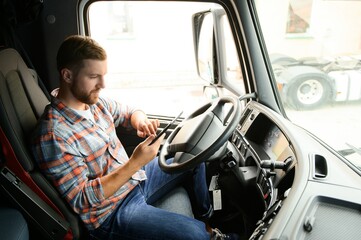 Man truck driver sitting behind wheel of car and holding digital tablet in his hands