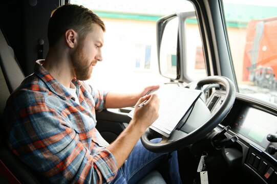 forwarder driver sits behind the wheel of a car and examines waybills documentation for the cargo.