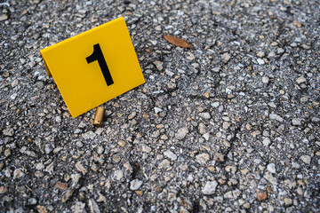 One yellow crime scene evidence marker on the street after a gun shooting brass bullet shell casing 9mm handgun pistol