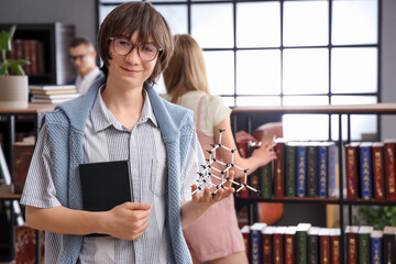 Male student with book and molecular model in library