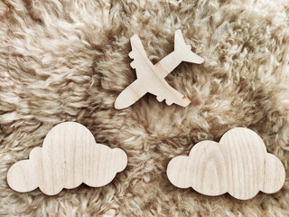 Fototapeta na wymiar Wooden toy airplane and clouds on a beige furry background. The concept of adventure tourism, travel enthusiasm, and flights. Plane crash