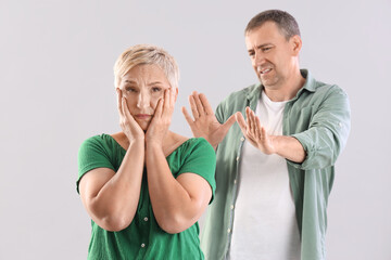 Mature couple quarreling on light background