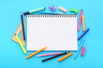 Composition with blank notebook and different stationery on color background