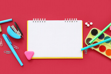 Composition with blank notebook and different stationery on red background