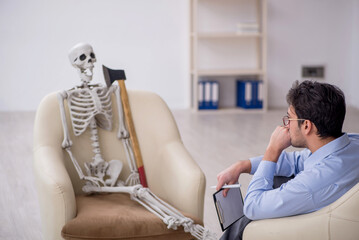 Young male psychologist meeting with skeleton