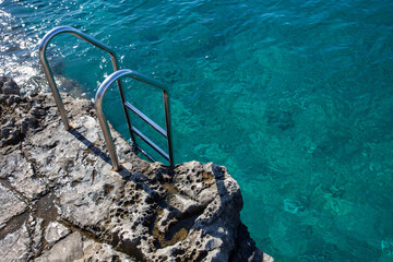 Fototapeta na wymiar Metal ladder for sea entrance on rock