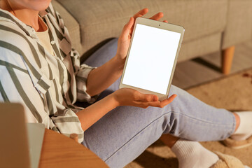 Young woman working with tablet computer at home in evening