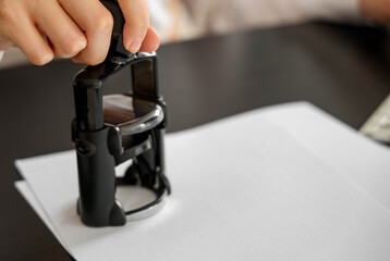 Young businesswoman stamping document at table in office, closeup
