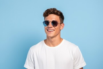 Young handsome and cool fictional person portrait. Guy smiling in casual white t-shirt. Isolated on a plain blue background. Generative AI.