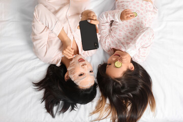 Asian mother with her little daughter taking selfie on bed, top view