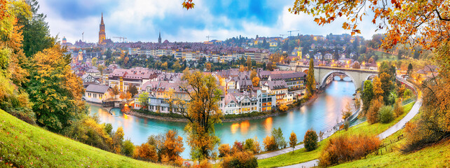 Fabulous autumn view of Bern city on  Aare river during evening with Pont de Nydegg bridge , cathedral of Bern and Nydeggkirche - Protestant church. - obrazy, fototapety, plakaty