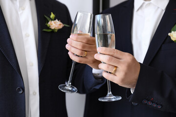 Happy gay couple with glasses of champagne on their wedding day, closeup