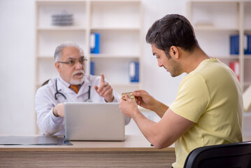 Fototapeta premium Young male patient visiting old male doctor