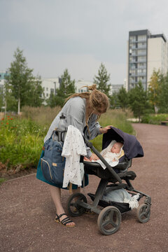 Woman putting baby to sleep in buggy at park during summer