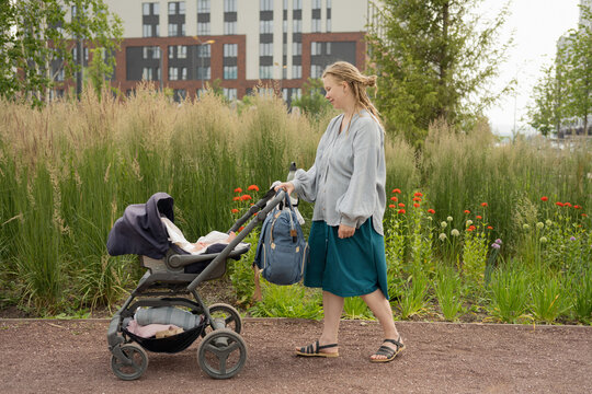 Woman pushing baby in stroller while walking in park