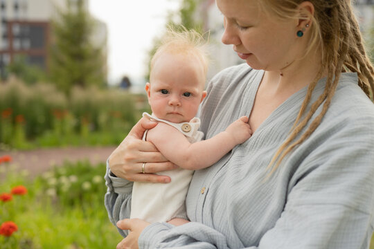 Woman carrying and hugging cute baby in park