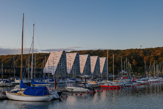 Outdoor exterior view at Vejle Havn Mole, row of yachts pier and the wave apartment during twilight sky in Vejle, Denmark.
